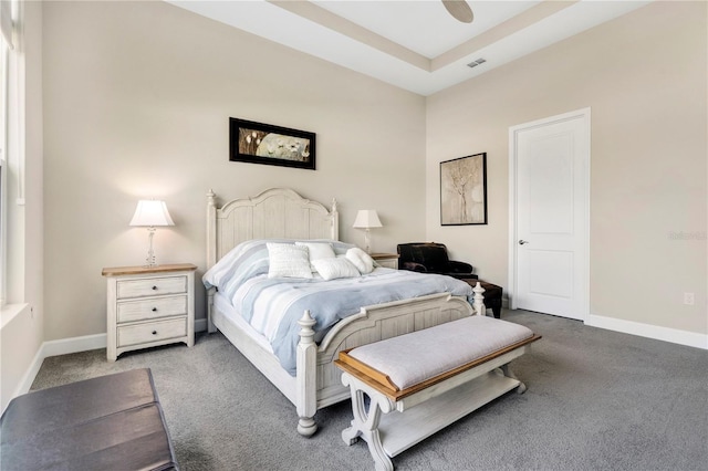 carpeted bedroom featuring ceiling fan and a raised ceiling