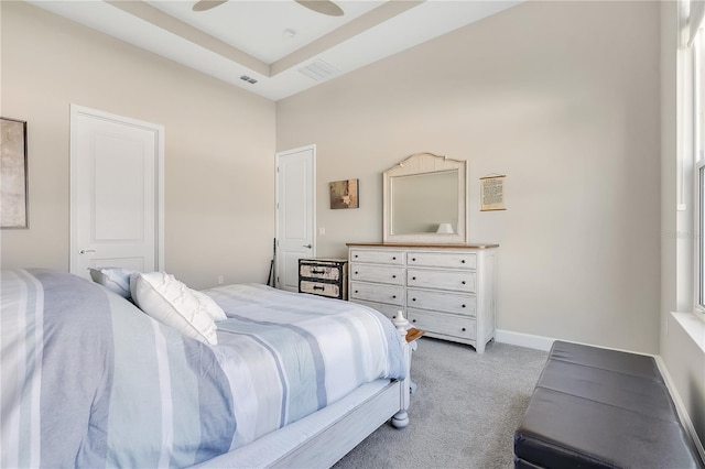 bedroom with a raised ceiling, ceiling fan, and light colored carpet