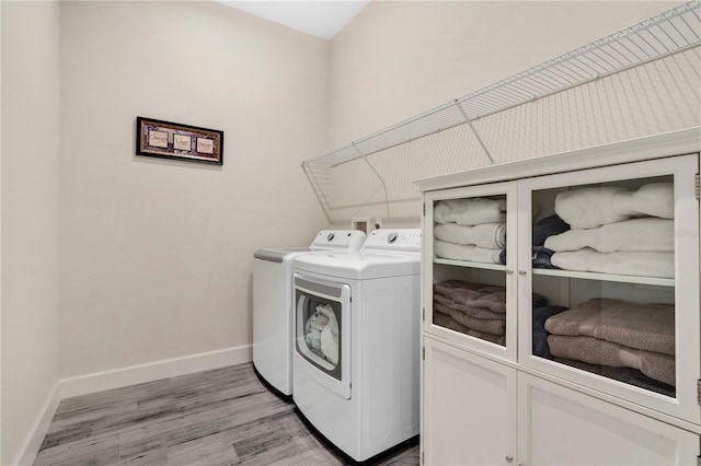 laundry room featuring cabinets, separate washer and dryer, and light hardwood / wood-style flooring