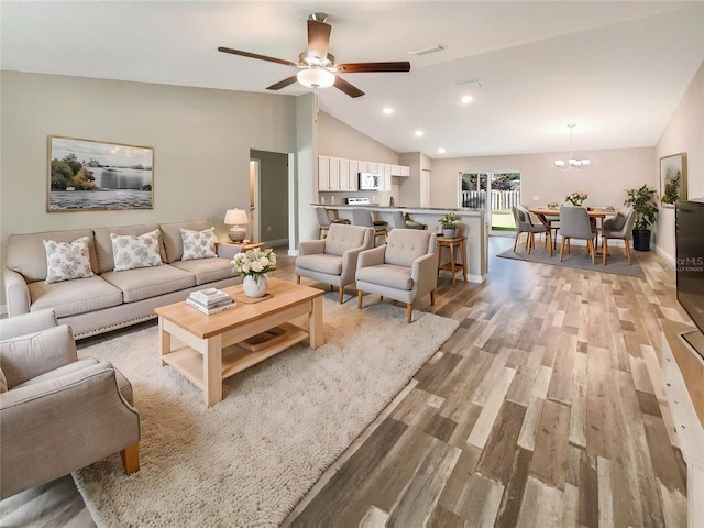 living room with ceiling fan with notable chandelier, light hardwood / wood-style floors, and high vaulted ceiling