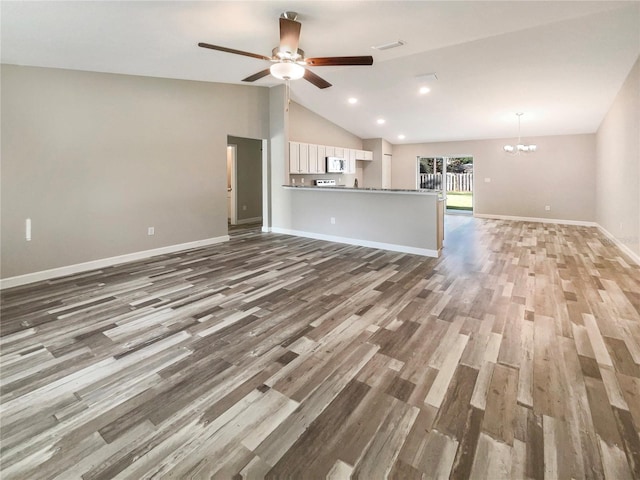 unfurnished living room with ceiling fan with notable chandelier, dark hardwood / wood-style flooring, and high vaulted ceiling