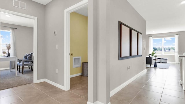 hallway with light tile patterned floors and a wealth of natural light