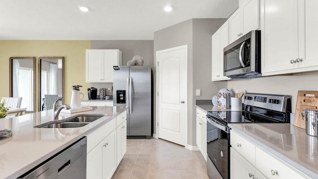 kitchen with light tile patterned floors, stainless steel appliances, white cabinetry, and sink