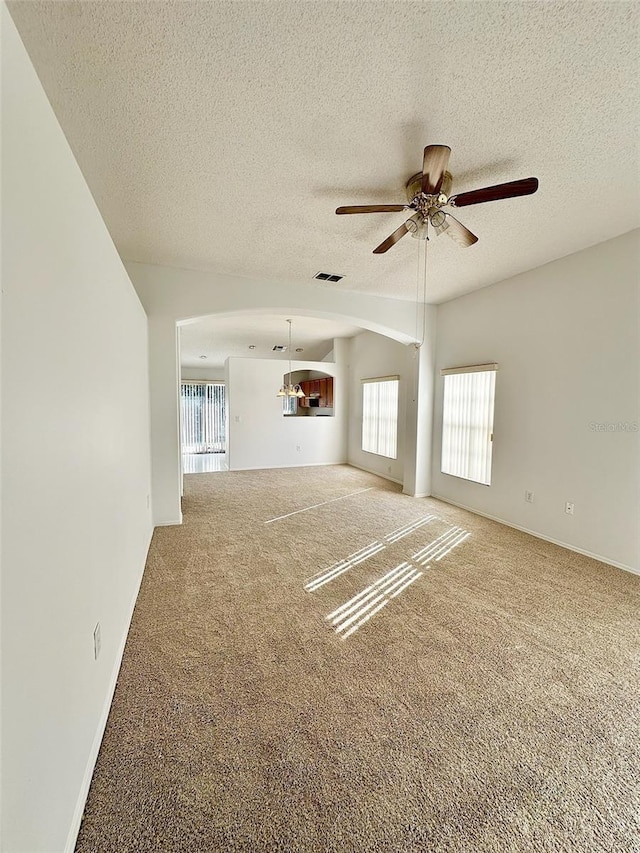 unfurnished living room with a textured ceiling, ceiling fan, carpet floors, and vaulted ceiling