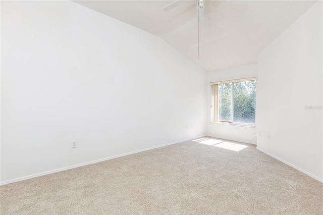 carpeted spare room featuring baseboards and vaulted ceiling