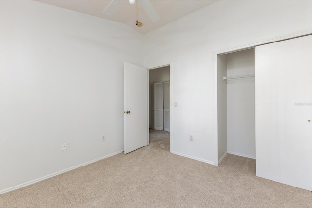 unfurnished bedroom with baseboards, light colored carpet, lofted ceiling, a closet, and a ceiling fan