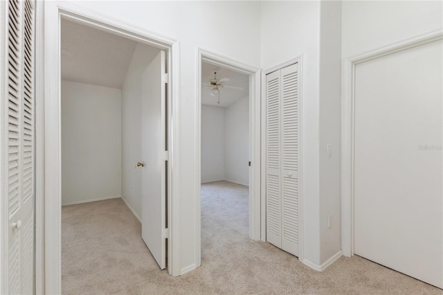 corridor with baseboards and light carpet