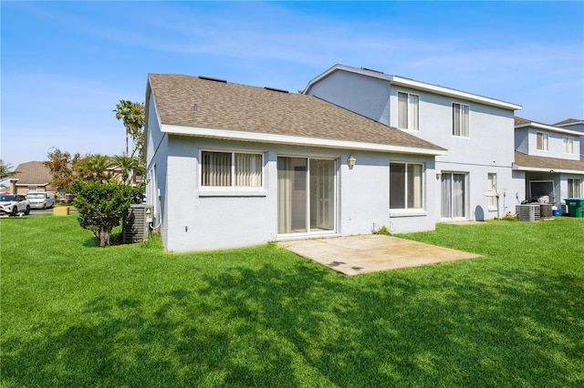 back of property with a yard, a shingled roof, and stucco siding