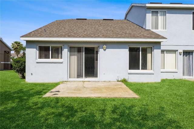 rear view of house with a patio, a lawn, roof with shingles, and stucco siding