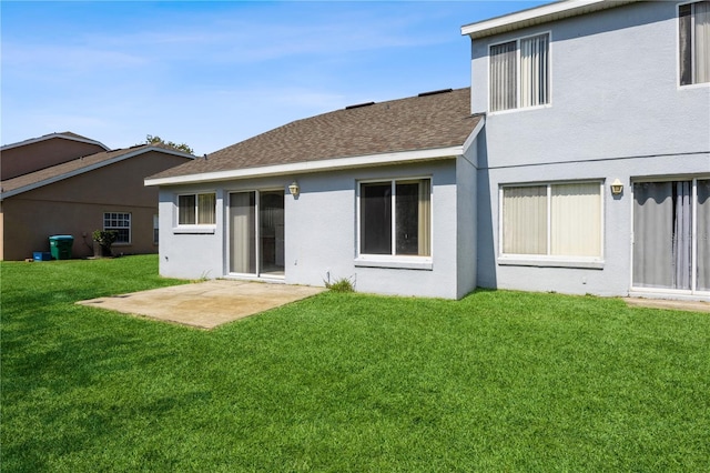 back of house with a shingled roof, a yard, a patio area, and stucco siding