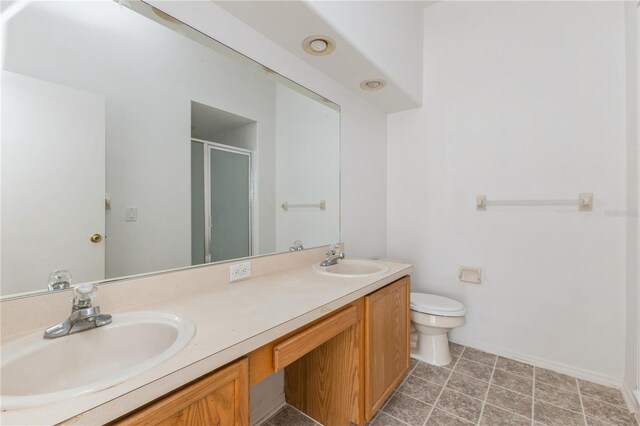 bathroom with double vanity, a stall shower, toilet, and a sink