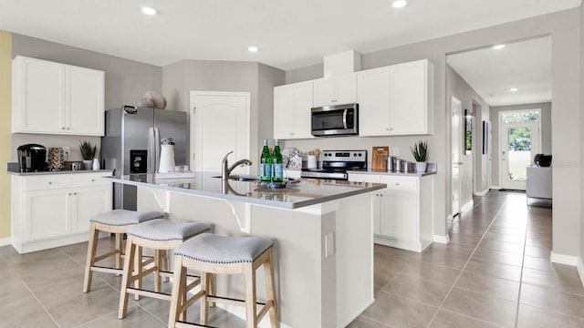 kitchen featuring white cabinets, stainless steel appliances, and an island with sink