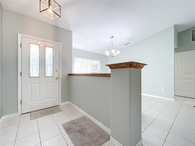 entrance foyer with light tile patterned floors, a chandelier, and a textured ceiling