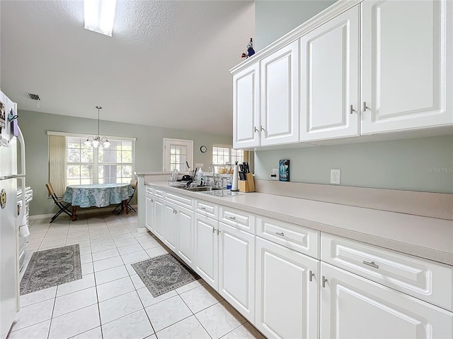 kitchen with plenty of natural light, light tile patterned flooring, white cabinetry, and sink