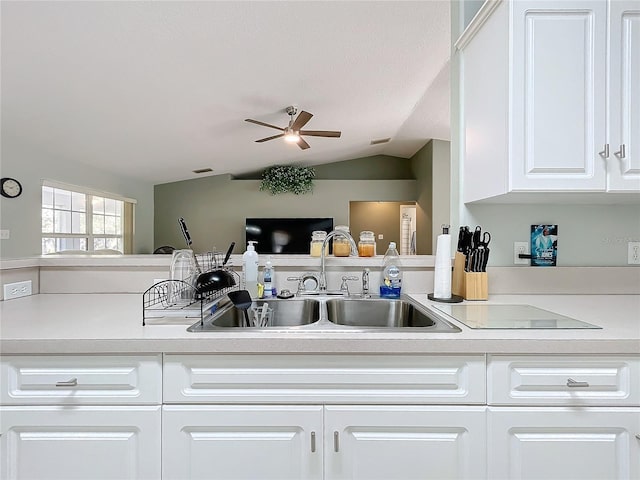 kitchen featuring ceiling fan, sink, white cabinets, and vaulted ceiling