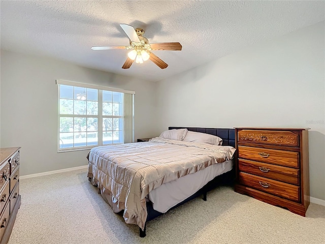 bedroom featuring ceiling fan, light colored carpet, and a textured ceiling