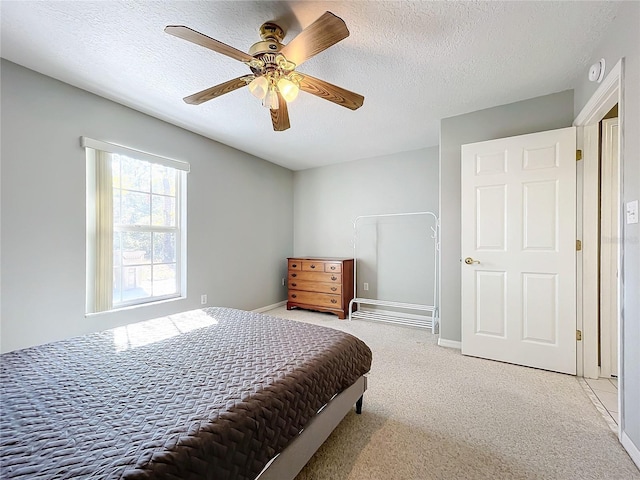 bedroom featuring ceiling fan, light colored carpet, and a textured ceiling