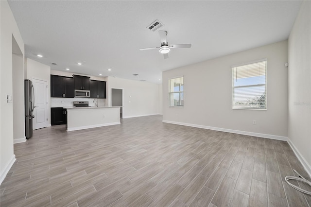 unfurnished living room featuring ceiling fan and sink