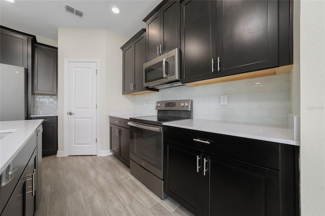 kitchen with backsplash, stainless steel appliances, and light hardwood / wood-style flooring