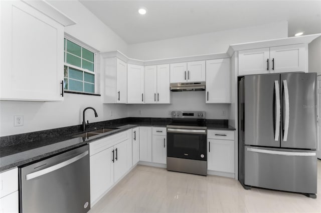 kitchen featuring appliances with stainless steel finishes, white cabinetry, dark stone countertops, and sink