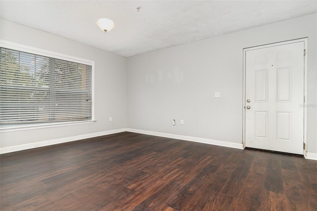 empty room with dark hardwood / wood-style floors and a textured ceiling