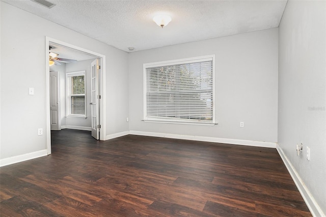 empty room with ceiling fan, dark wood-type flooring, and a textured ceiling