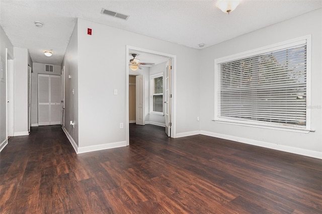 unfurnished room featuring a textured ceiling, ceiling fan, and dark wood-type flooring