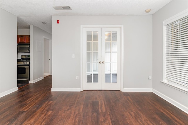 empty room with french doors, dark hardwood / wood-style flooring, a textured ceiling, and ceiling fan