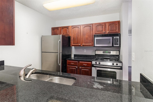 kitchen featuring dark stone countertops, sink, a textured ceiling, and appliances with stainless steel finishes