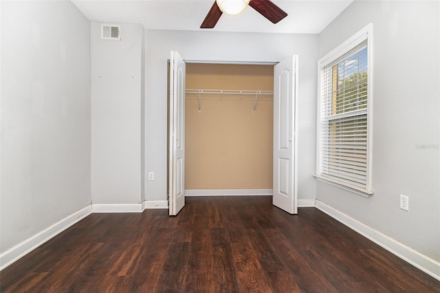 unfurnished bedroom with dark hardwood / wood-style flooring, a closet, and ceiling fan