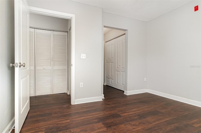 unfurnished bedroom featuring a textured ceiling, a closet, and dark hardwood / wood-style floors