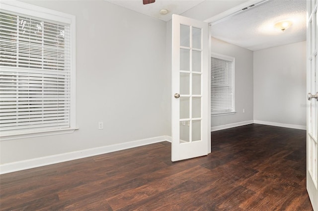 spare room featuring dark hardwood / wood-style floors, a textured ceiling, and french doors