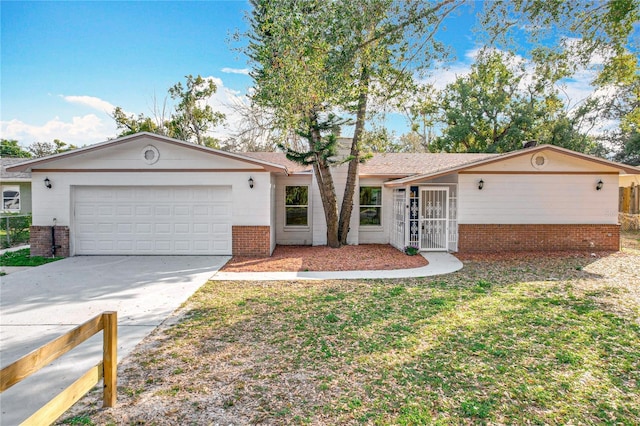 single story home with a garage, concrete driveway, brick siding, and a front yard