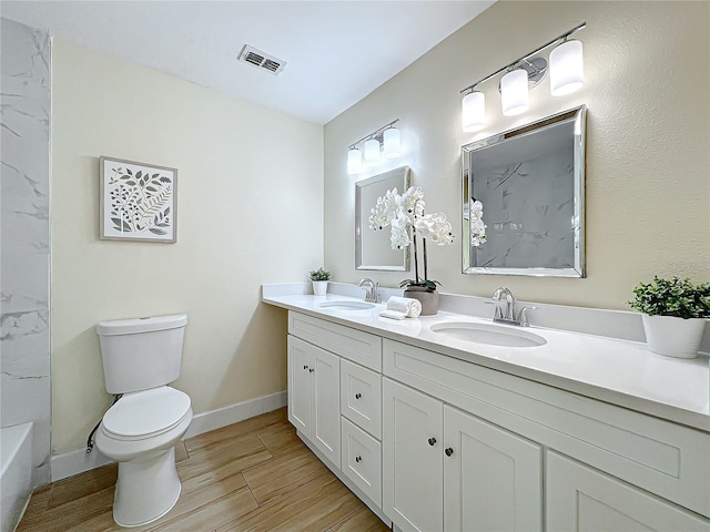 bathroom with toilet, visible vents, a sink, and wood finished floors