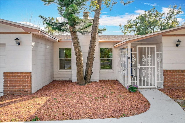 doorway to property with a garage and brick siding