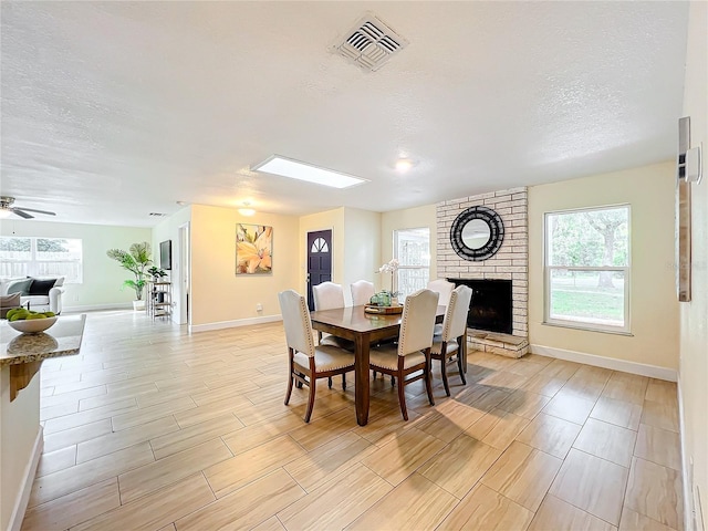 dining room featuring plenty of natural light, visible vents, a fireplace, and a textured ceiling