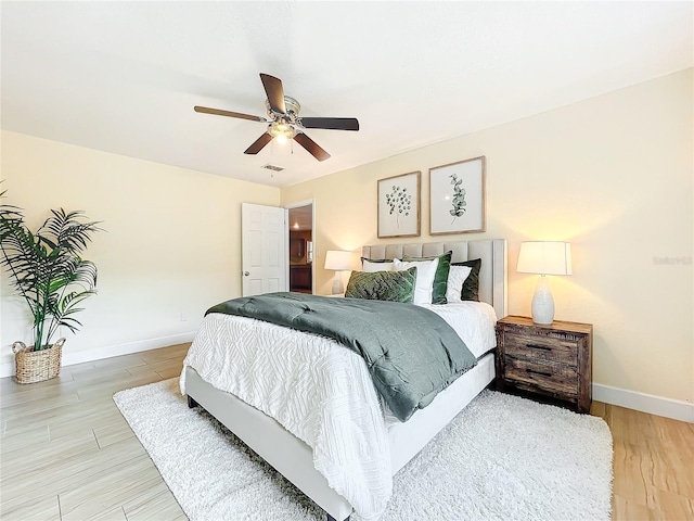 bedroom with ceiling fan, wood finished floors, visible vents, and baseboards