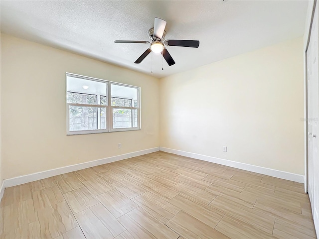 spare room featuring a ceiling fan, wood tiled floor, a textured ceiling, and baseboards