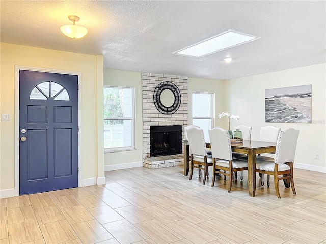 dining area featuring a brick fireplace, a textured ceiling, and baseboards