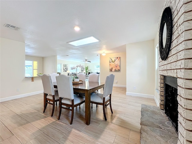 dining space featuring visible vents, a stone fireplace, and baseboards