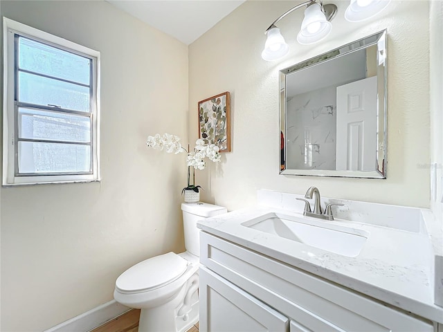 bathroom featuring toilet, baseboards, and vanity