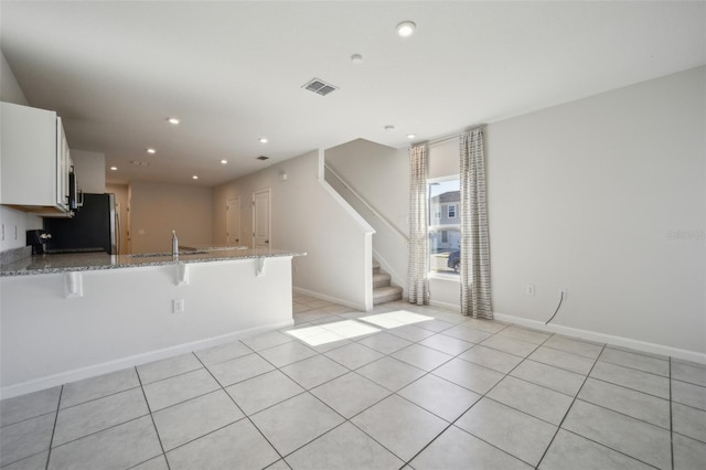 kitchen with white cabinetry, light stone countertops, a breakfast bar area, and kitchen peninsula