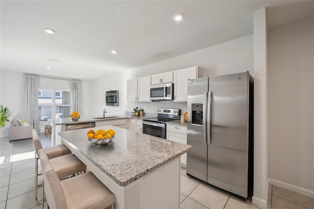 kitchen featuring a center island, appliances with stainless steel finishes, a kitchen breakfast bar, and kitchen peninsula