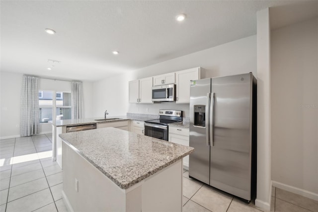 kitchen with light tile patterned flooring, sink, white cabinetry, appliances with stainless steel finishes, and kitchen peninsula