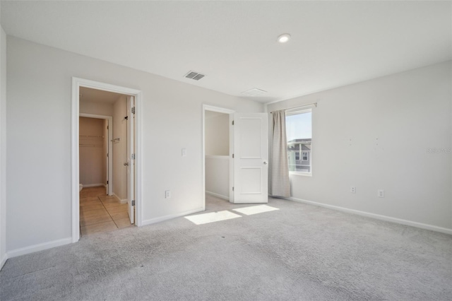 unfurnished bedroom featuring a walk in closet and light carpet