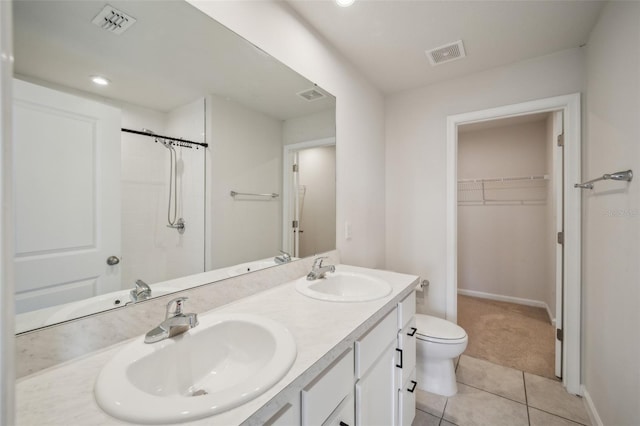 bathroom featuring tile patterned floors, toilet, vanity, and a shower