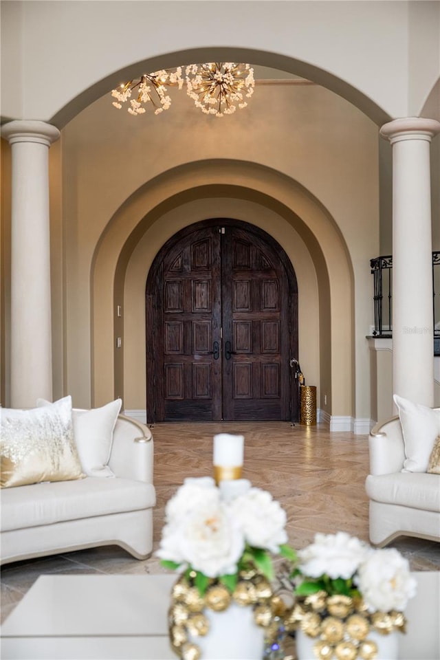 living room featuring ornate columns and a notable chandelier