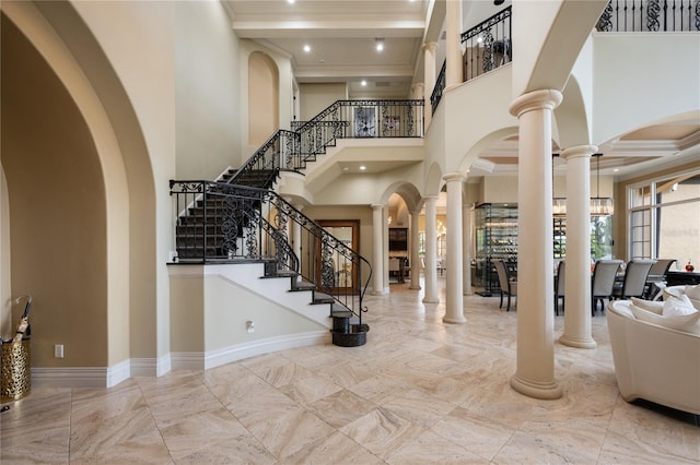 entryway featuring a towering ceiling, ornate columns, and a notable chandelier