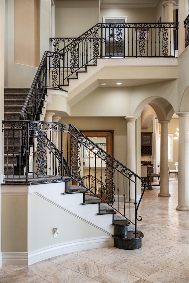 staircase featuring decorative columns and a high ceiling