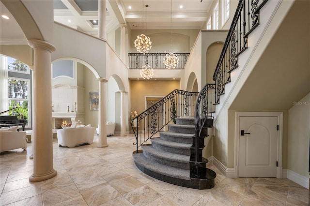 entrance foyer with a towering ceiling, decorative columns, an inviting chandelier, and ornamental molding